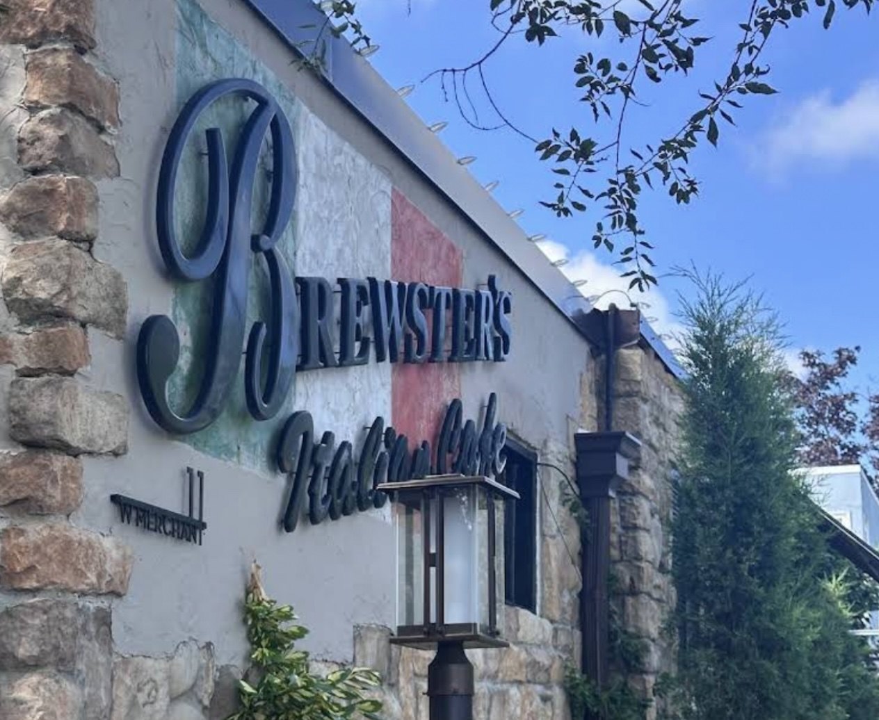 Brewster's Italian Cafe, a stone corner building with flowers, patio tables and a heat lamp.