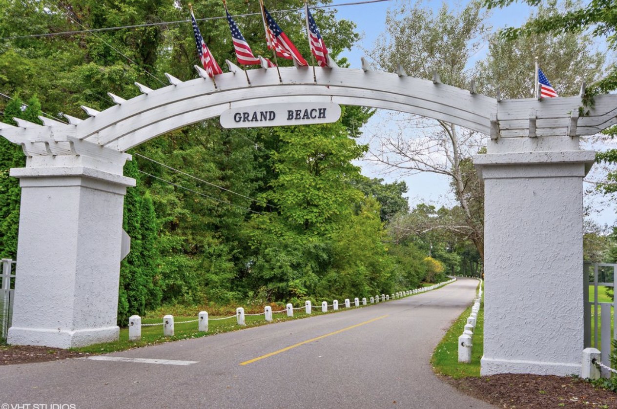 The white arched Grand Beach entry gate, flying American flags over the village road.